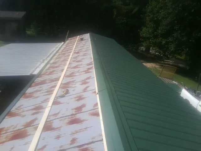 Old rusted panels beside newly installed green metal roofing — Wind Damage Roof Repair by Roofing Brothers in Mattawa