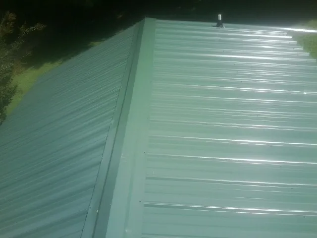 New green metal panels meeting at the ridge of a roof — Flat Roof Repair work by our crew in Mattawa