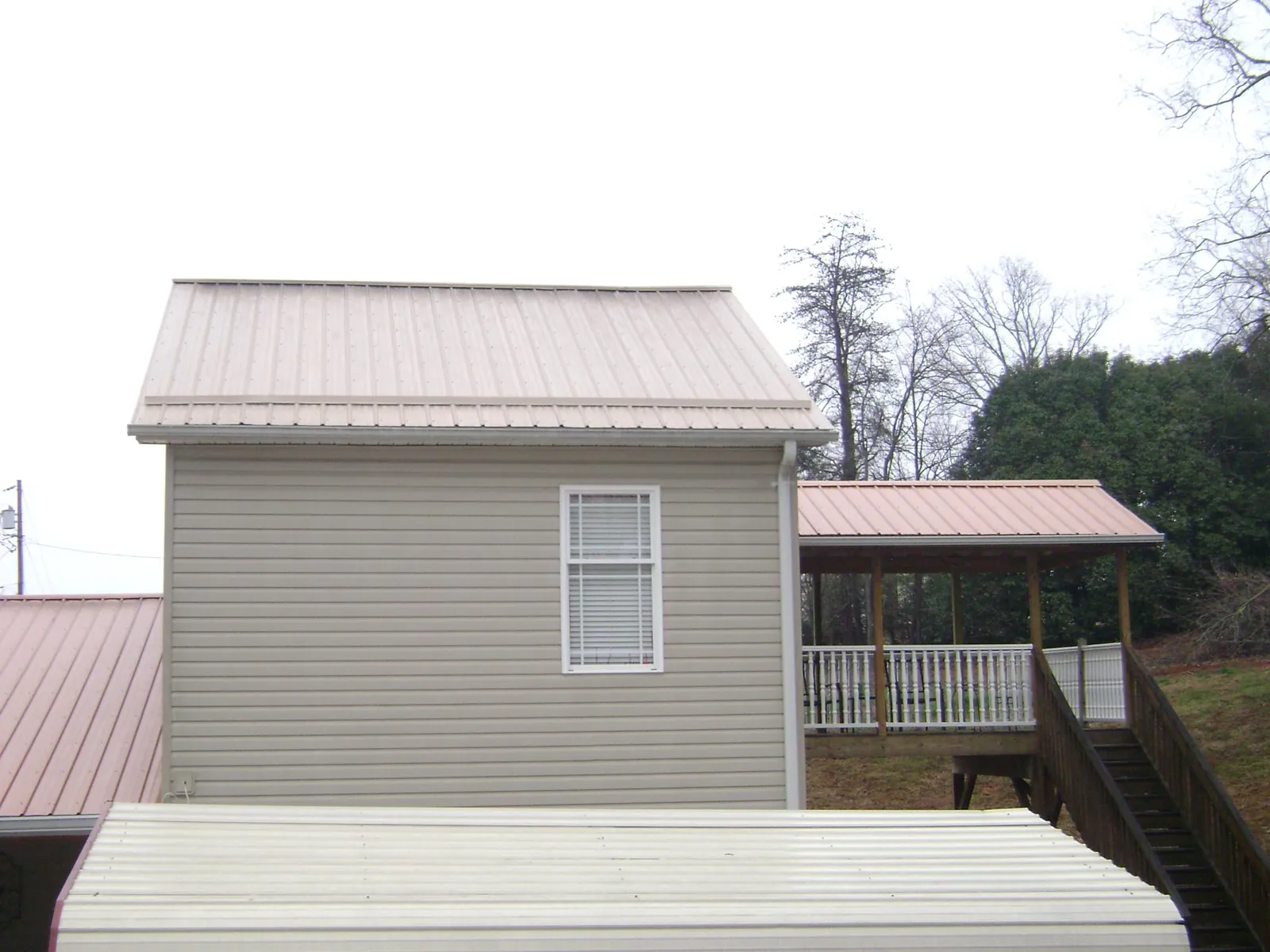 Tan metal roofs on a two story addition and attached porch, from a Roof Replacement job in Mattawa